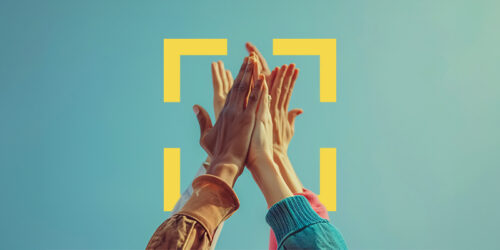 Diverse hands coming together in a high-five against a blue sky, with yellow corner-bracket graphics framing the scene.
