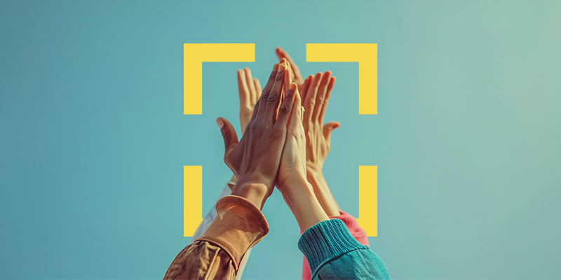 Diverse hands coming together in a high-five against a blue sky, with yellow corner-bracket graphics framing the scene.