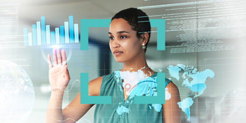 Businesswoman taps a futuristic touchscreen with a world map and bar charts displayed on the holographic interface.