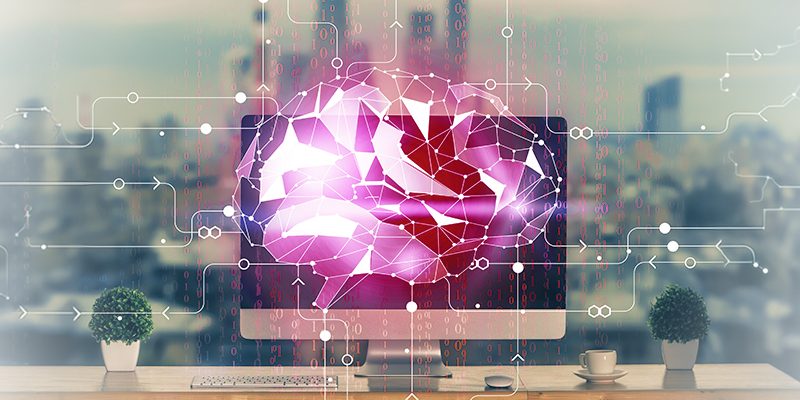 Pink geometric AI brain displayed on a computer monitor, with circuit lines over a desk setup.