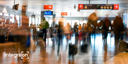 Blurred photograph of a hallway in an airport, with heavy traffic of people coming and going.